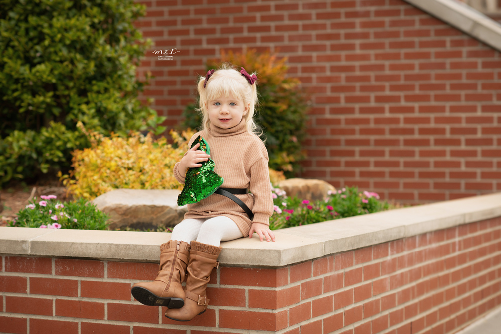 young child sitting with a sequined Christmas tree pillow